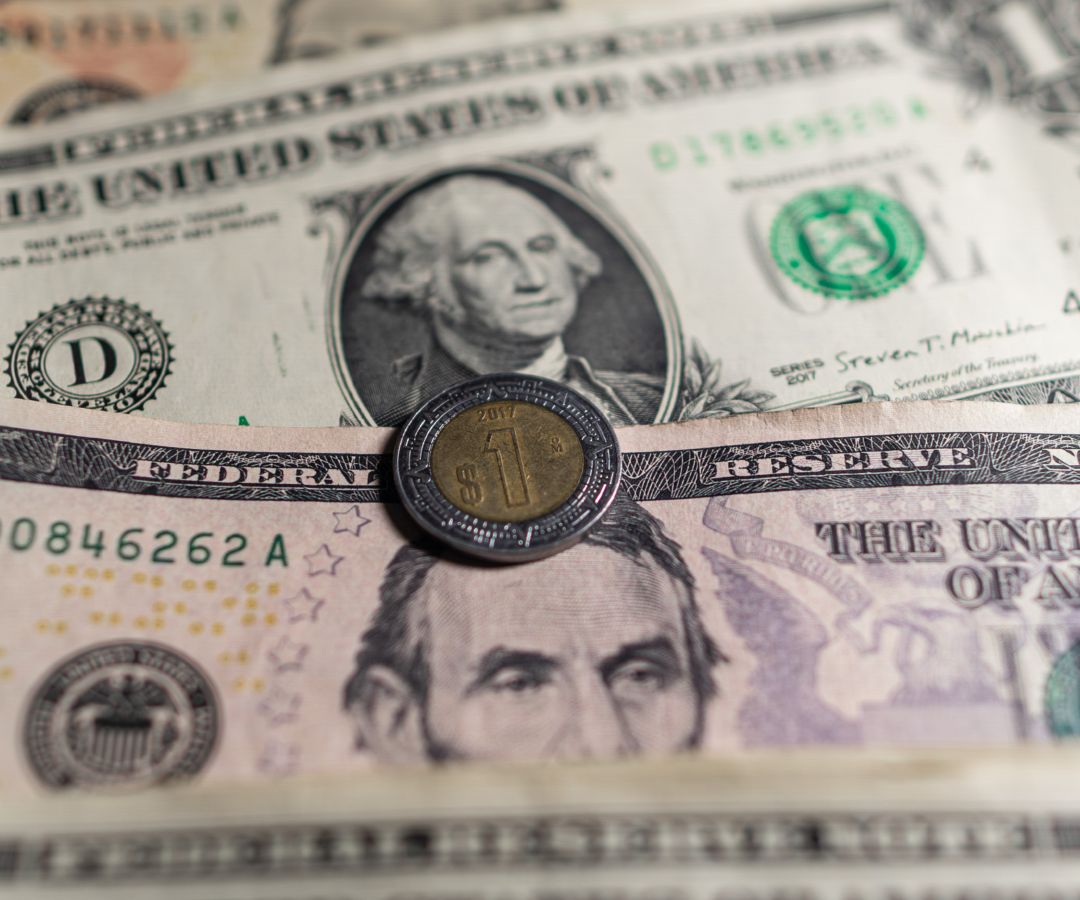 Billetes de dólar y una moneda de un peso mexicano. Foto: N+